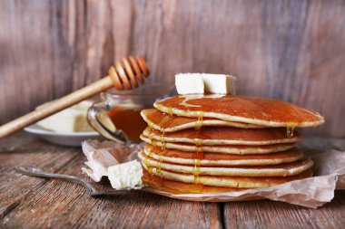 Bal ve rustik ahşap arka plan üzerine tereyağı ile krep yığını