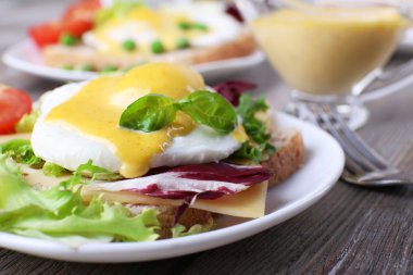 Yumurta Benedict ile tost ve ahşap masa üzerinde tabakta domates