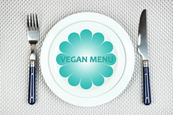 Plaat met tekst Vegan Menu, vork en mes op tafellaken achtergrond — Stockfoto