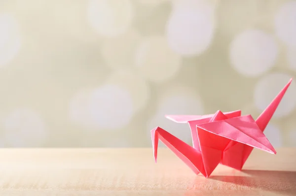 Origami crane på träbord, på ljus bakgrund — Stockfoto