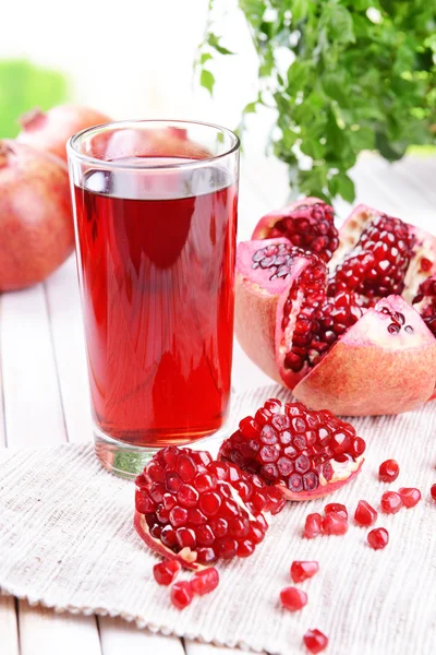 Melograni maturi con succo sul tavolo su sfondo chiaro — Foto Stock