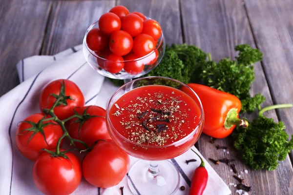 Tomato juice in goblet and fresh vegetables on napkin on wooden background — Stock Photo, Image