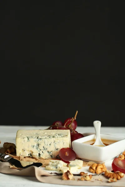 Natureza morta com queijo azul saboroso na mesa, no fundo escuro — Fotografia de Stock