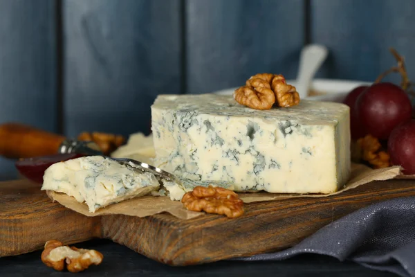 Still life with tasty blue cheese on table, on wooden background