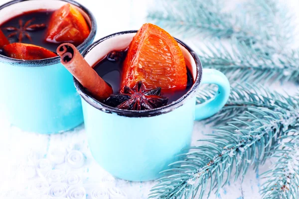 Mugs of mulled wine with pieces of orange and spice on snow covered background — Stock Photo, Image