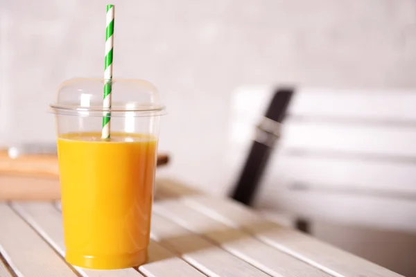 Апельсиновый сок в фаст-фуде закрытая чашка с трубкой на деревянном столе и светлом фоне стены — стоковое фото
