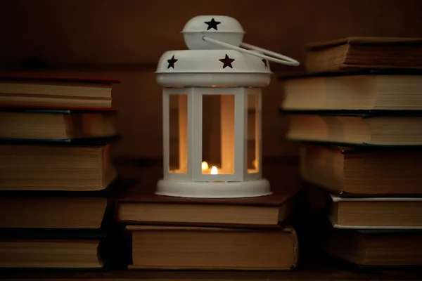 Books and decorative lantern on table and wooden planks background — Stock Photo, Image