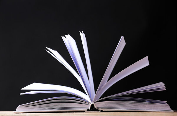 Открытая книга по деревянной поверхности

