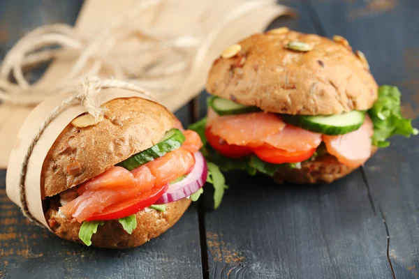 Sandwiches con salmón y verduras sobre fondo de madera — Foto de Stock