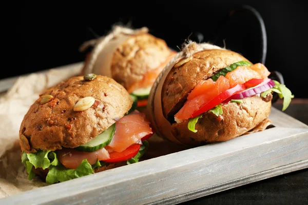 Broodjes met zalm op lade, op donkere achtergrond — Stockfoto