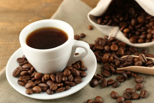 Kopje koffie met bonen op rustieke houten achtergrond — Stockfoto