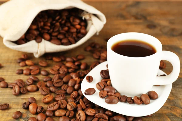 Taza de café con frijoles sobre fondo rústico de madera — Foto de Stock