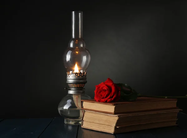 Lâmpada de querosene com livros e rosa vermelha — Fotografia de Stock
