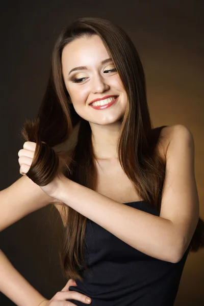 Krásná mladá žena s dlouhými vlasy na tmavě hnědé pozadí — Stock fotografie