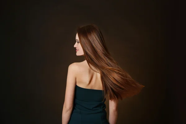 Hermosa joven con el pelo largo sobre fondo marrón oscuro — Foto de Stock