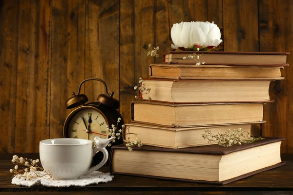 Cup of tea with books and clock on wooden background — Stock Photo, Image