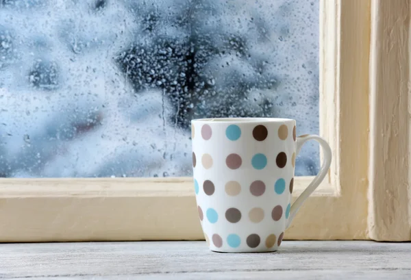 Cup of hot drink on windowsill on rain background — Stock Photo, Image