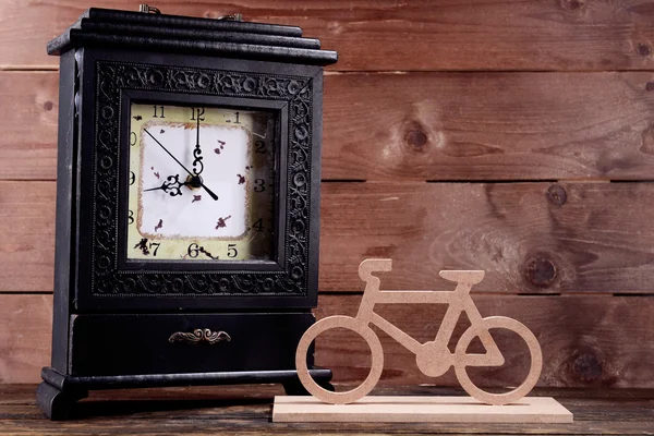 Horloge rétro avec vélo décoratif sur table sur fond bois — Photo