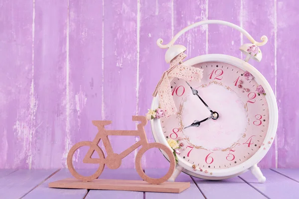 Beautiful vintage alarm clock with decorative bicycle on table on wooden background — Stock Photo, Image