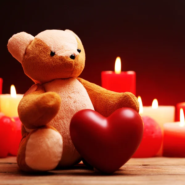 Urso de pelúcia com coração vermelho e velas — Fotografia de Stock