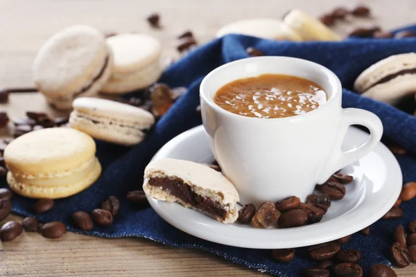 Macarons colorés doux et café en tasse sur fond de table en bois — Photo