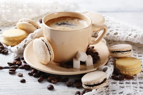 Macaroons coloridos suaves e café na caneca na cor de fundo de madeira — Fotografia de Stock