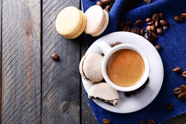 Makaroni yang lembut dan berwarna-warni dan kopi dalam cangkir di atas meja kayu latar belakang, tampilan atas — Stok Foto