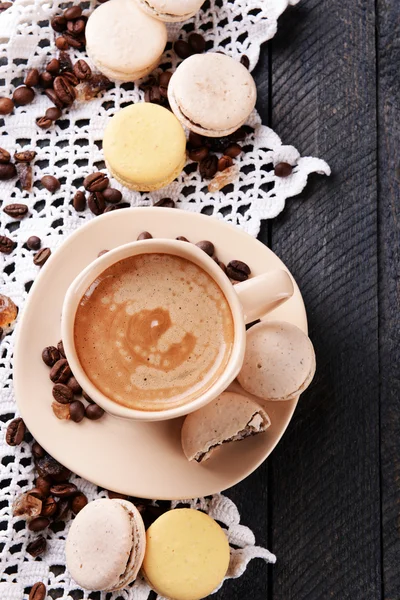 Makaroni yang lembut dan berwarna-warni dan kopi dalam cangkir pada latar belakang meja kayu — Stok Foto