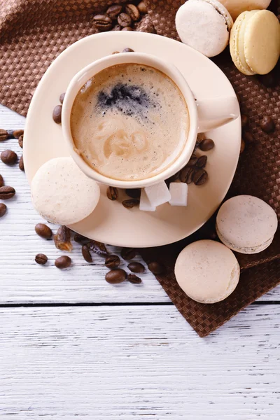 Makaroni lembut berwarna-warni dan kopi dalam cangkir pada warna latar belakang kayu — Stok Foto