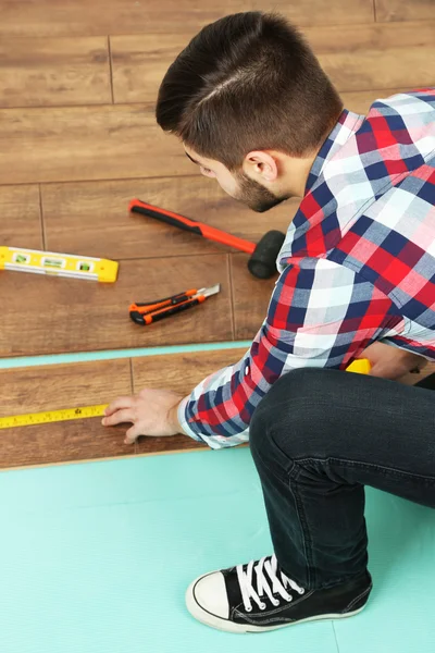 Timmerman installeert laminaat vloeren in de kamer — Stockfoto