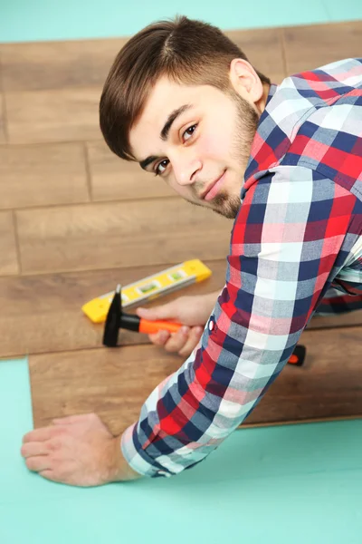 Trabalhador de carpinteiro instalando piso laminado na sala — Fotografia de Stock