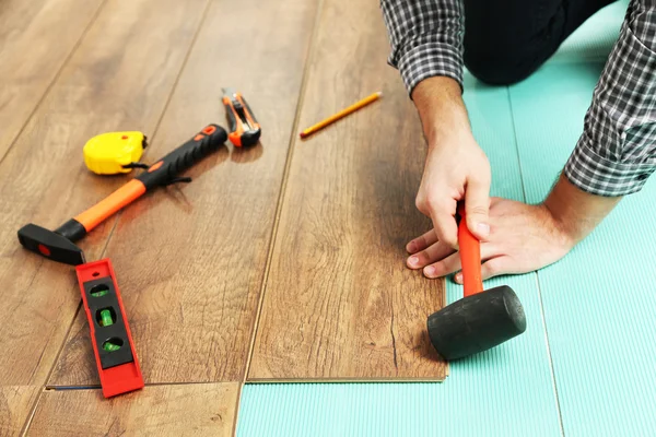 Trabalhador de carpinteiro instalando piso laminado na sala — Fotografia de Stock