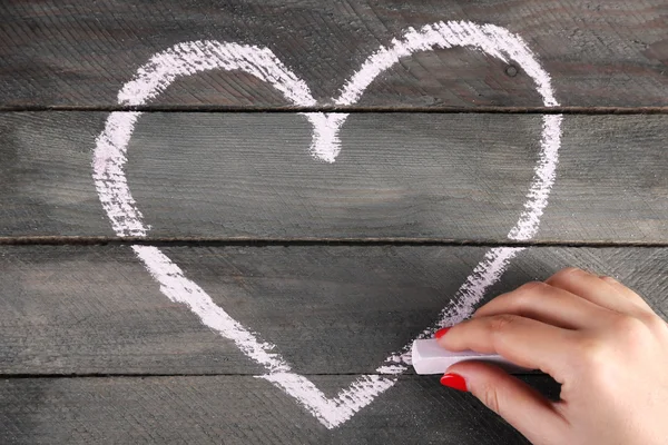 Ruka kreslí srdcem křídy na dřevěné desce — Stock fotografie