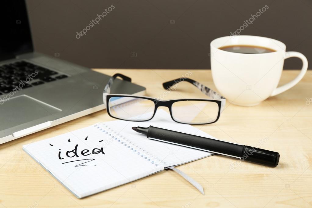 Cup of coffee with note Idea in notebook