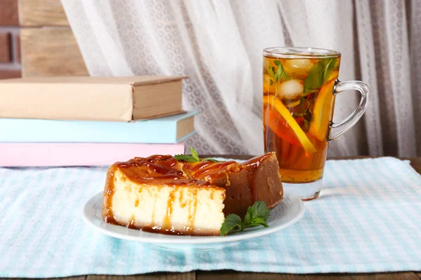 Cheese cake in plate, cup of tea and books on tablecloth on curtain background — Stock Photo, Image