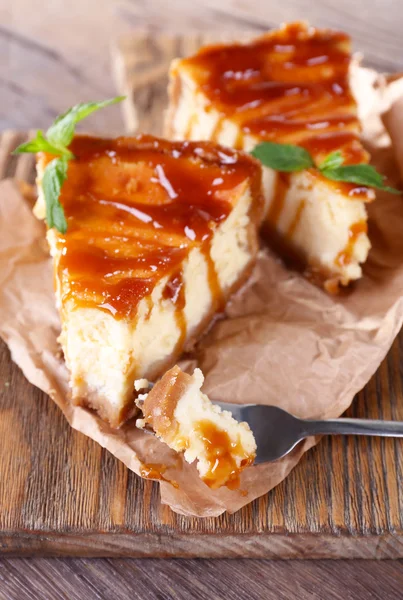 Cheesecake op stuk papier op snijplank op houten achtergrond — Stockfoto