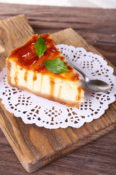 Cheesecake op papier servet op snijplank op houten tafel op lichte achtergrond — Stockfoto