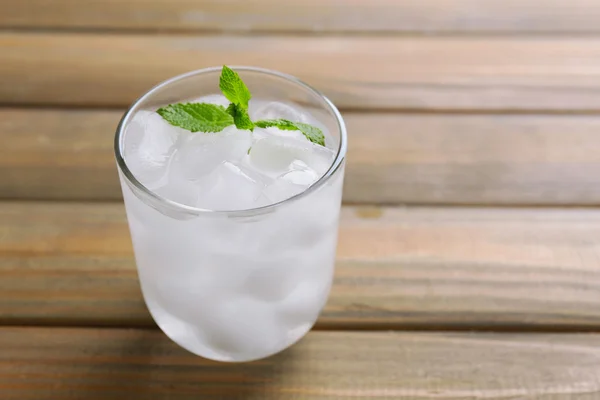 Glass with ice cubes on wooden table — Stock Photo, Image