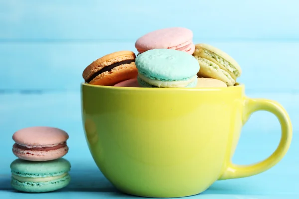 Sortiment av mjuka färgglada macaroons i färgglad mugg på färg trä bakgrund — Stockfoto