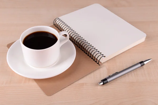 Tasse Kaffee auf Untertasse mit Notizbuch und Stift auf Holztischhintergrund — Stockfoto