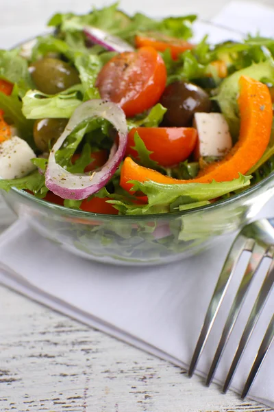 Griekse salade in glas schotel op servet en kleur houten achtergrond — Stockfoto