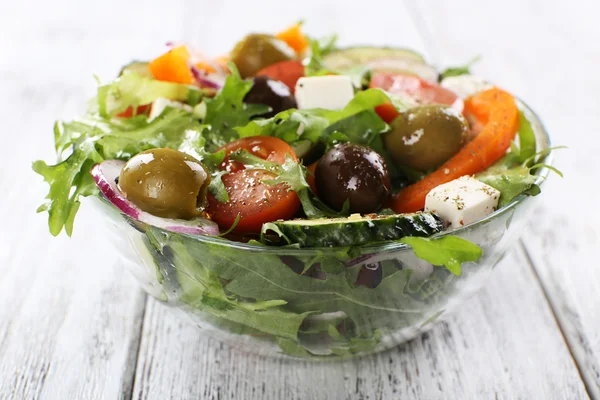 Greek salad in glass dish on color wooden table background — Stock Photo, Image