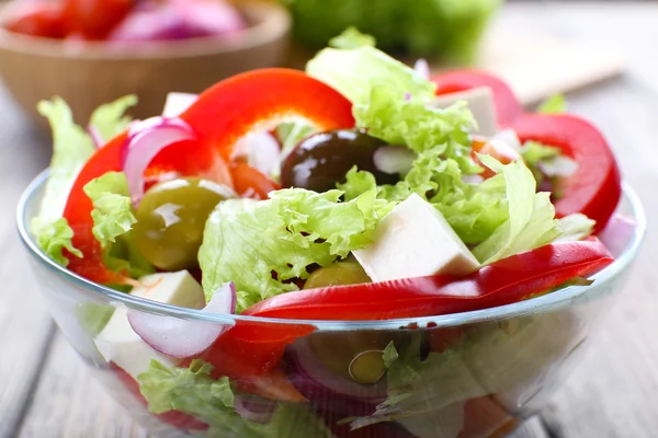 Griekse salade in glas schotel op houten tafel achtergrond — Stockfoto