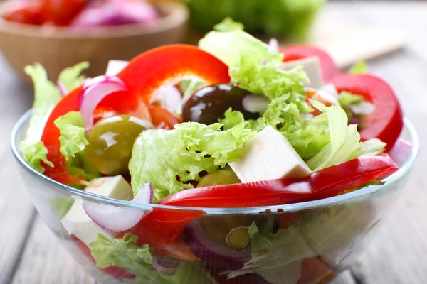 Salada grega em prato de vidro em fundo de mesa de madeira — Fotografia de Stock