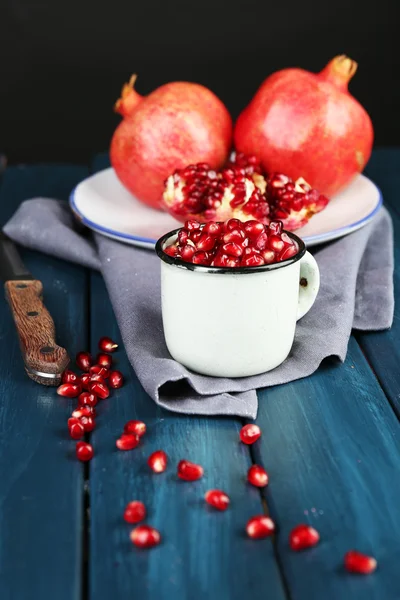 Juicy ripe pomegranate on wooden table, on dark background — Stock Photo, Image