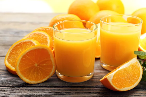 Copo de suco de laranja e fatias em fundo de mesa de madeira — Fotografia de Stock