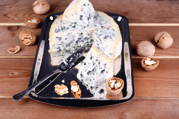 Blue cheese with nuts and blade on metal tray and wooden table background — Stock Photo, Image