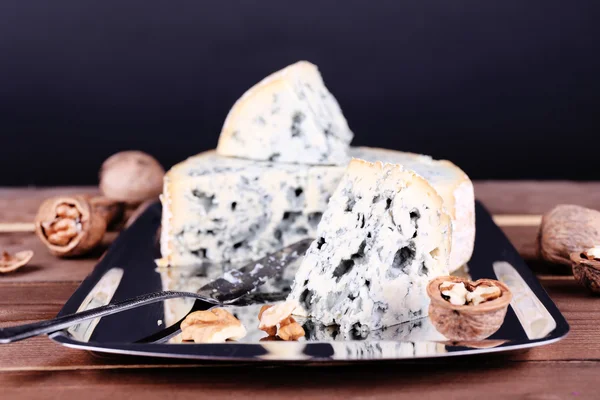 Blue cheese with nuts and blade on metal tray and wooden table and dark background — Stock Photo, Image