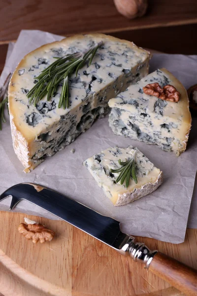 Queijo azul com raminhos de alecrim e nozes a bordo com faca e mesa de madeira fundo — Fotografia de Stock