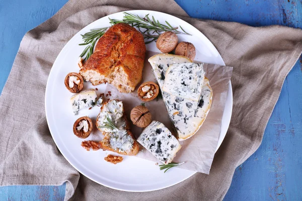 Queso azul con ramitas de romero, pan y nueces en plato con tela de arpillera y fondo de mesa de madera de color —  Fotos de Stock